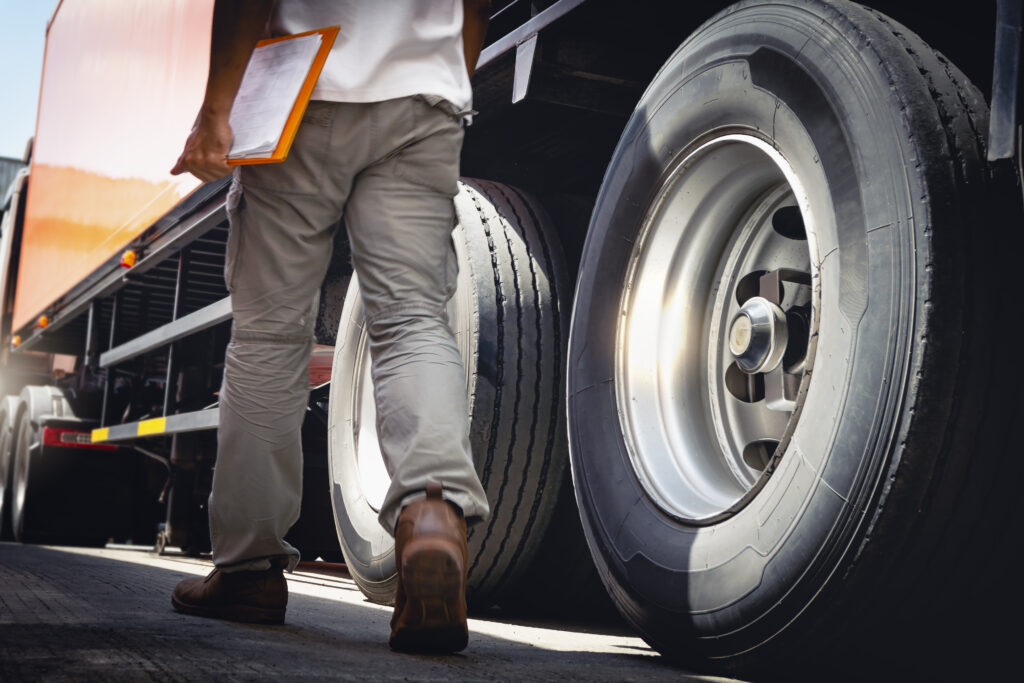 Truck Driver is Checking the Truck's Safety Maintenance Checklist. Lorry. Inspection Semi Truck Wheels and Tires. Freight Truck Transportation.